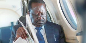 A photo of former Prime Minister Raila Odinga reading a past edition of the Star newspaper. 
