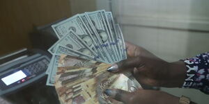 An employee at a forex bureau holding a thousand Kenyan notes and a hundred dollar bills
