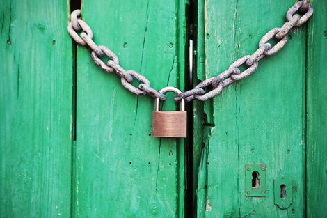 File image of a door locked with a chain link and a padlock.