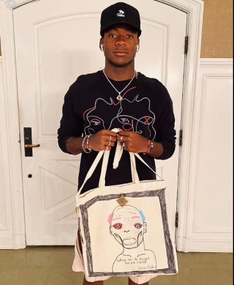 Singer Madonna's adopted son David Banda posses with one of the canvas bags she handmade
