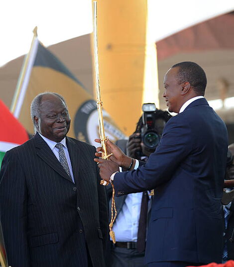 President Uhuru Kenyatta receives a sword as a symbol of authority from former president Mwai Kibaki during his inauguration at the Moi International Sports Center Kasarani in Nairobi on April 9, 2013