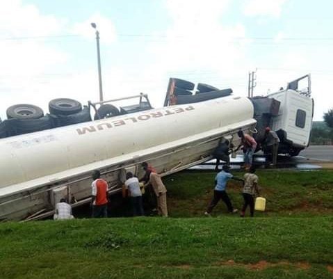 Residents and passersby siphoning fuel from the lorry that was involved in an accident in Kamara. Police moved in to cordon the scene and diverted the vehicles to another path.