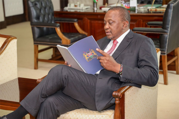 President Uhuru Kenyatta reads through the Building Bridges Initiative (BBI) report after receiving it from the task force at State House, Nairobi on November 26, 2019.