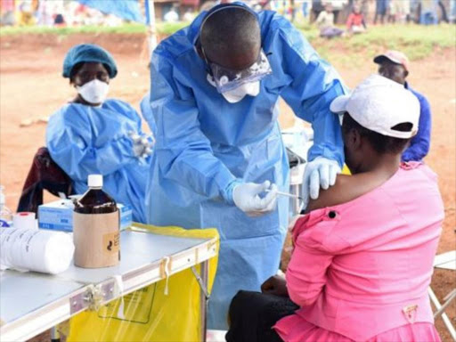 Health workers vaccinating people against Ebola to prevent the spread of the virus