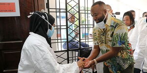 Governor Hassan Joho gets his hands sanitized before inspection of a medical facility