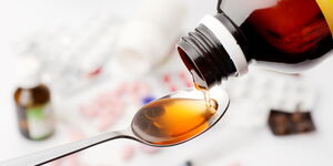 An image of a cough syrup being poured on a spoon.