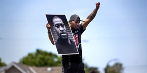 A protester, Tony L. Clark, raises a George Floyd poster outside the Cup Food convenience store in Mineapolis on Thursday, May 28, 2020.