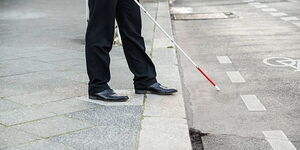 A file image of a blind man walking with the assistance of a cane