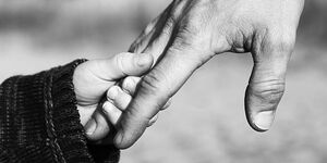 A file image of a father and son holding hands.