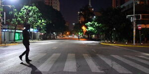 A man crossing a street in Nairobi at Night.