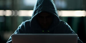 Undated file image of an individual with a hidden face working on a computer.