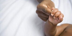 A mother holding her child's hands in hospital.