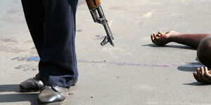 A police officer walks past one of bodies of the suspects at the scene of the shooting on Langata road, Nairobi on January 19, 2011