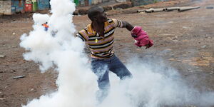 A protestor hurling a teargas canister.