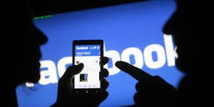A silhouette image of people using the Facebook application.