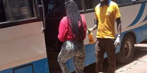 A tout stands watch at the matatu doors armed with a hand sanitizer, sterile gloves and a mask.