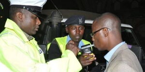 A traffic police officer administers the breathalyzer test to driver in a previous operation