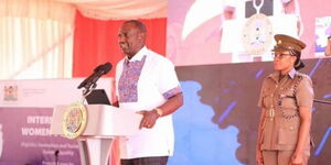 Lieutenant Colonel Damaris Agnetta clad in army fatigue stands behind President William Ruto on February 2, 2023.