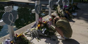 A family member grieves in front of a cross honoring one of her kins killed in this week's elementary school shooting in Uvalde, Texas, Thursday, May 26, 2022.