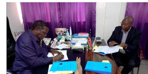 COTU Sec-Gen Francis Atwoli (left) inks a salary increament deal in the presence of a guest on Monday, November 1, 2021.