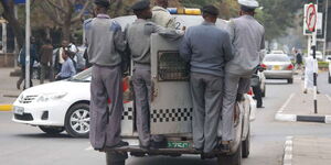 County enforcement officers hang on an old Jalopy while performing duties in Nairobi CBD.
