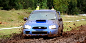 A blue Subaru speeding in the mud