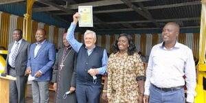 Father Romano Filipe holding up his Kenyan Citizenship certificate handed by Health Cabinet Secretary Mutahi Kagwe during his celebration of fifty years of priesthood on February 28, 2021.