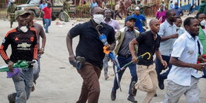 Ferry passengers flee from police firing tear gas, at the ferry in Mombasa, Kenya Friday, March 27, 2020.