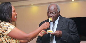 Former President Mwai Kibaki (right) enjoys a piece of cake during a past celebration.