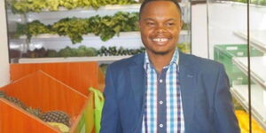 Goldenscape CEO Peter Wangai stands next to some of the produce from his greenhouses.