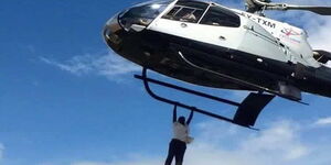 A Kenyan man hanging on a plane during burial of businessman Jacob Juma on May 13, 2016 