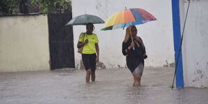 Mombasa residents walk through a flooded section on Nyerere Avenue following heavy rains on October 17, 2019.