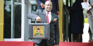 Former Treasury CS Henry Ritich holding the budget briefcase in June 2015.