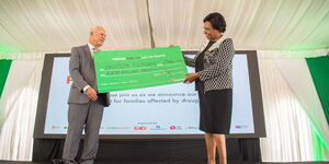 Safaricom Board Chairman Michael Joseph (left) hands over a cheque worth Ksh100 million towards the Pamoja Tuungane Campaign.