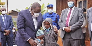 Interior Cabinet Secretary Fred Matiang'i (Left) and Inspector General of Police Hillary Mutyambai pictured with the children of the late Police Constable John Njenga on July 28, 2020.