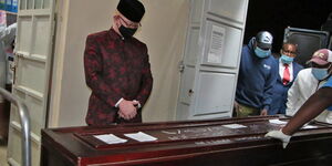 Nominated Senator Isaac Mwaura looking at the coffin bearing remains of Agnes Wangui