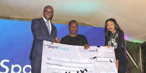 Jackpot winner Samuel Abisai (Center) receives a Ksh221 million cheque from Sportpesa CEO Ronald Karauri (left).