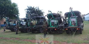KDF officers standing next to the trucks donated by the force to fight locusts