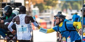 Claus-Henning Schulke hands over a bottle to double Olympic champion Eliud Kipchoge during the Berlin marathon race held in Germany.