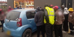 Locals surround a vehicle after a the driver is found dead inside on Saturday August 12, 2023