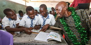 Education Cabinet Secretary Ezekiel Machogu poses with students during the distribution of food to learners in Turkana on April 7, 2023. 