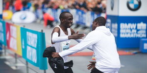 Marathoner Eliud Kipchoge hugs his coach Patrick Sang during a competition in 2018