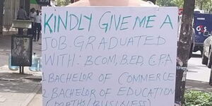Samuel Meeme with a placard on his back begging for a job.