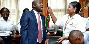 Photo of Kipchumba Murkomen receiving a cake from a member of his staff at his offices on March 12, 2020.