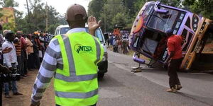 An NTSA official marshalls traffic at a past accident scene