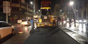Road contractors recarpeting Moi Avenue at night 
