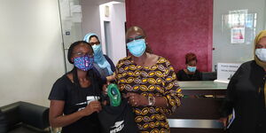 Navalayo and Industrialization CS Betty Maina pose for a photo holding Enda Shoes at Umoja Rubber Company in October,2020.