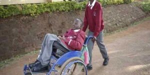 Nicodemus Kilunda being wheeled by a colleague at Lenana School in 2018.