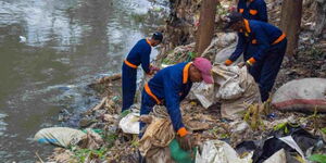 People collecting garbage along a river