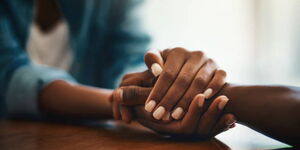 Two people holding hands in a loving way.